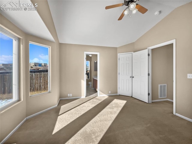 unfurnished bedroom featuring ceiling fan, lofted ceiling, carpet flooring, and ensuite bath