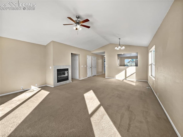 unfurnished living room with ceiling fan with notable chandelier, carpet flooring, and vaulted ceiling