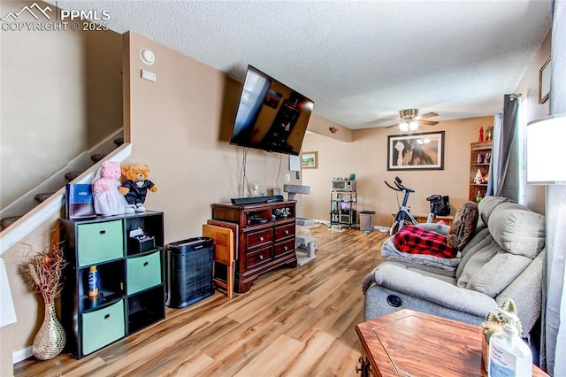 living room with hardwood / wood-style flooring, ceiling fan, and a textured ceiling