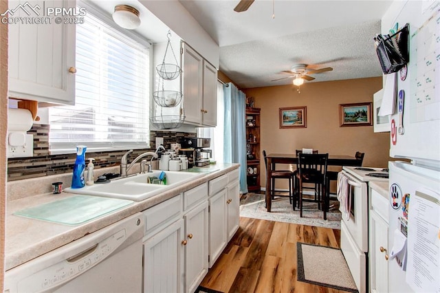 kitchen featuring sink, white appliances, white cabinetry, a textured ceiling, and decorative backsplash