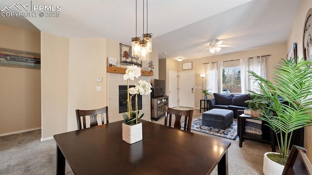 carpeted dining room featuring a tiled fireplace and ceiling fan