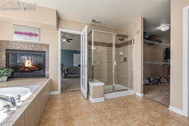 bathroom with tile patterned floors, plus walk in shower, a tiled fireplace, and a textured ceiling