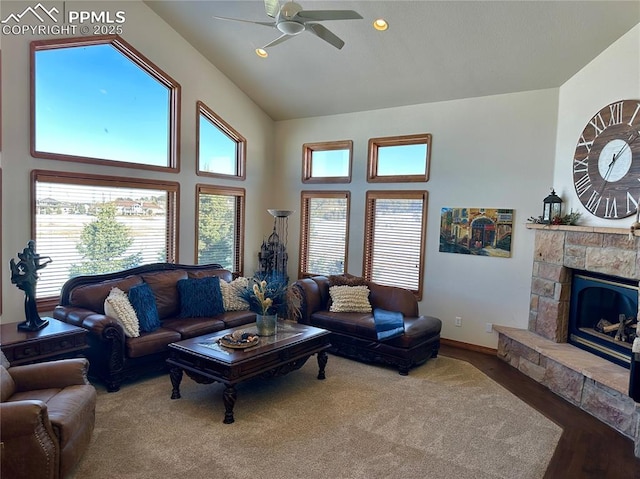 living room with plenty of natural light, hardwood / wood-style floors, a stone fireplace, and high vaulted ceiling