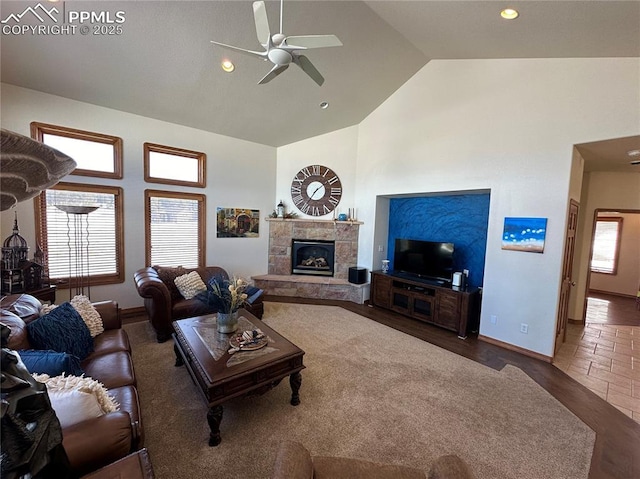 living room featuring a stone fireplace, high vaulted ceiling, and ceiling fan