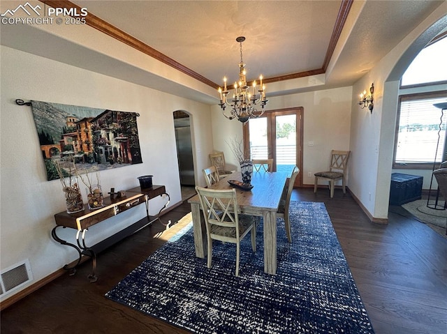 dining space featuring ornamental molding, a healthy amount of sunlight, a tray ceiling, and dark hardwood / wood-style flooring