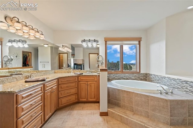 bathroom featuring tile patterned flooring, vanity, and tiled bath