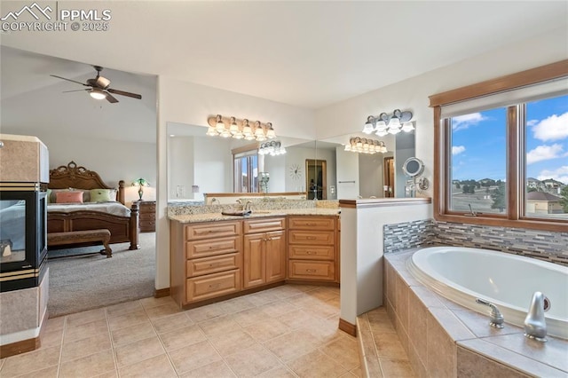 bathroom featuring vaulted ceiling, vanity, ceiling fan, tiled bath, and tile patterned flooring