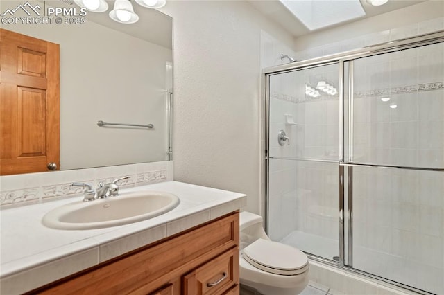 bathroom featuring vanity, toilet, and a shower with shower door