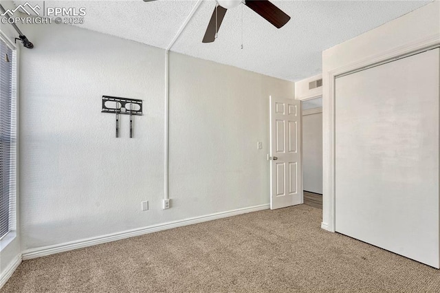 unfurnished bedroom with a textured ceiling, a closet, ceiling fan, and carpet