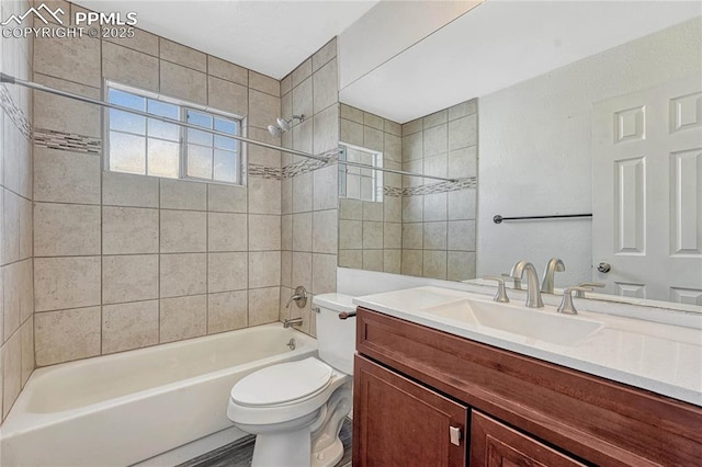 full bathroom featuring vanity, tiled shower / bath combo, and toilet