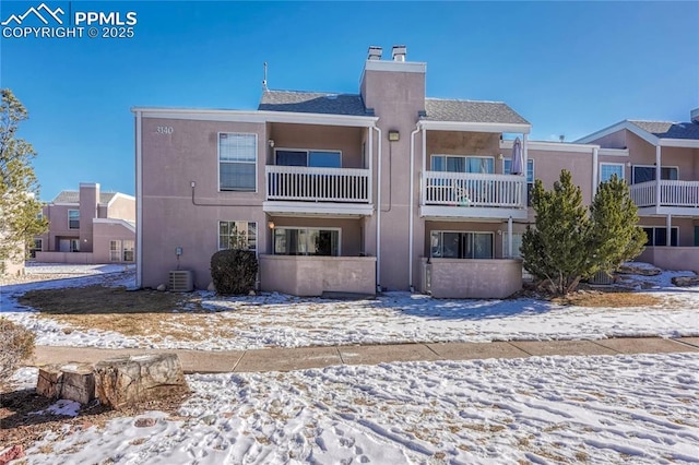 snow covered house featuring cooling unit