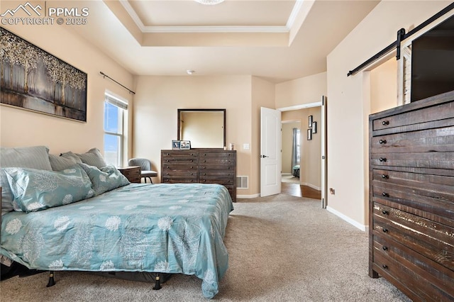 carpeted bedroom featuring a tray ceiling, ornamental molding, and a barn door