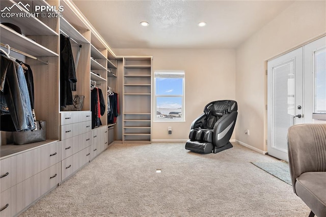 walk in closet featuring light colored carpet and french doors