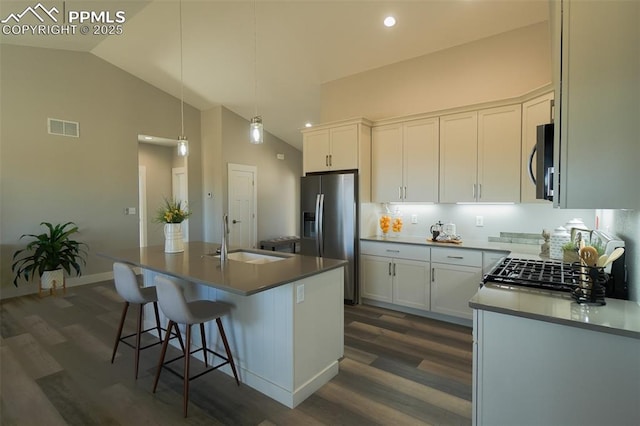 kitchen featuring an island with sink, stainless steel fridge with ice dispenser, sink, and white cabinets