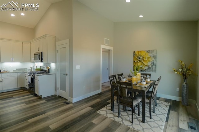 dining space featuring dark wood-type flooring and high vaulted ceiling