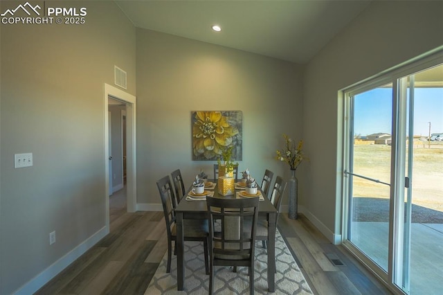 dining area with vaulted ceiling and dark wood-type flooring