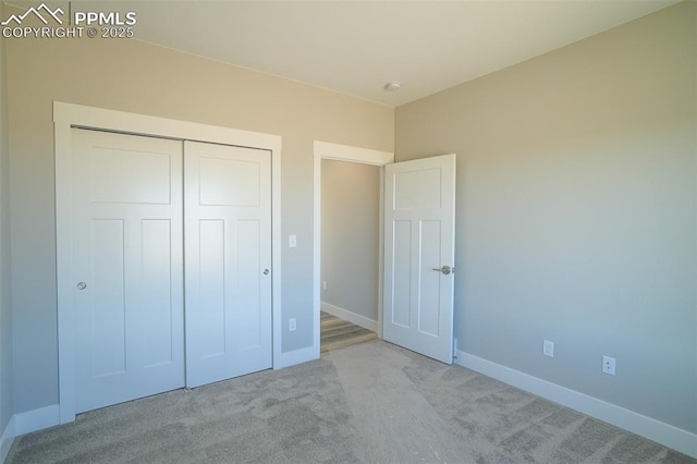 unfurnished bedroom with light colored carpet and a closet