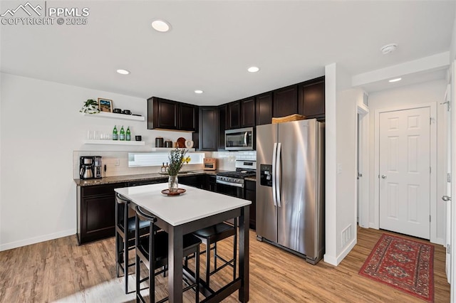 kitchen featuring tasteful backsplash, appliances with stainless steel finishes, dark brown cabinets, and light hardwood / wood-style floors