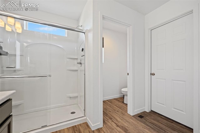 bathroom with a shower with door, wood-type flooring, vanity, and toilet