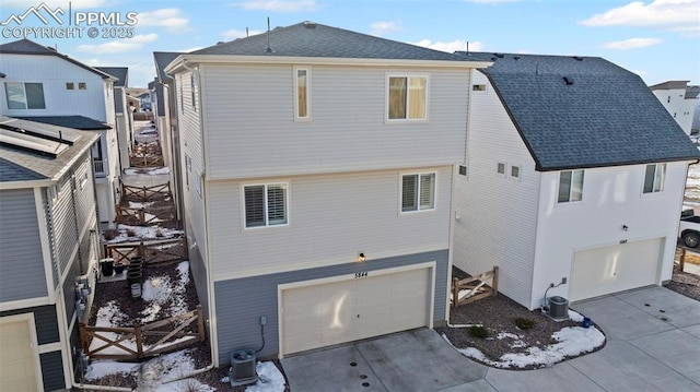 back of property with a garage and central air condition unit