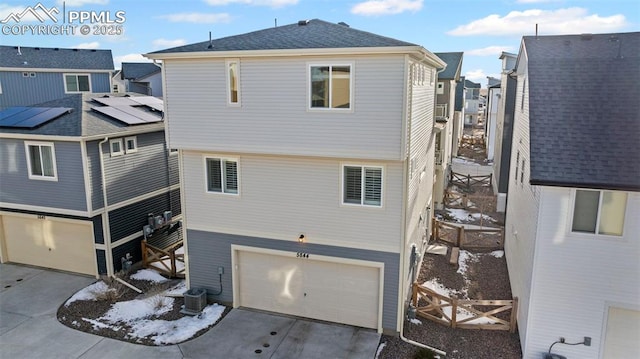 rear view of property with a garage and central AC unit