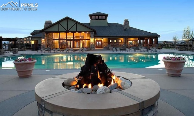 pool at dusk featuring a patio and an outdoor fire pit