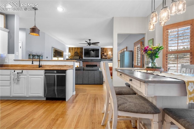 kitchen featuring white cabinetry, wood counters, decorative light fixtures, and dishwasher