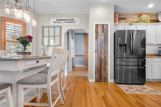 kitchen with white cabinetry, backsplash, stainless steel fridge with ice dispenser, and pendant lighting