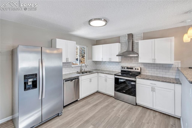 kitchen featuring white cabinets, stainless steel appliances, sink, and wall chimney range hood