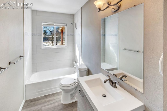 full bathroom featuring vanity, tiled shower / bath, hardwood / wood-style flooring, and toilet