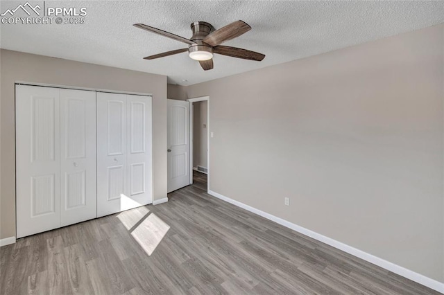 unfurnished bedroom with ceiling fan, a closet, light hardwood / wood-style flooring, and a textured ceiling