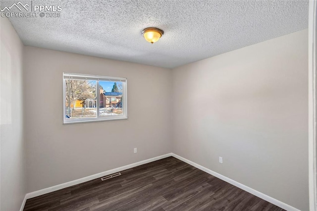 spare room featuring dark hardwood / wood-style floors and a textured ceiling