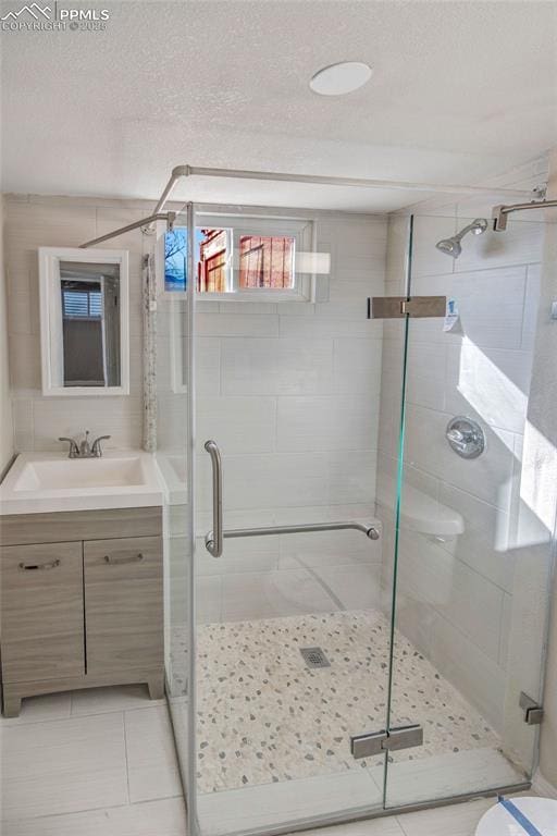 bathroom with vanity, tile patterned flooring, a shower with shower door, and a textured ceiling