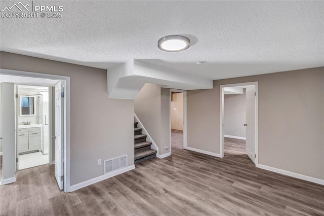 basement with wood-type flooring, sink, and a textured ceiling