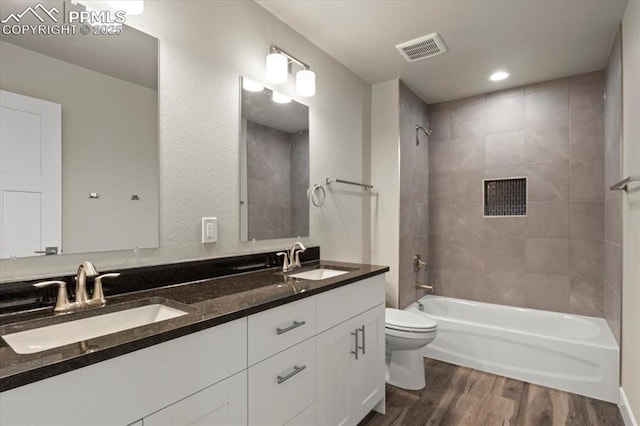 full bathroom with tiled shower / bath, hardwood / wood-style floors, vanity, and toilet