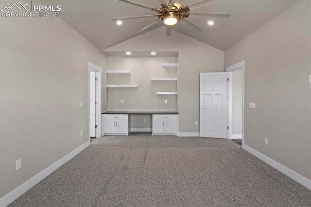 interior space with vaulted ceiling, carpet flooring, and built in desk