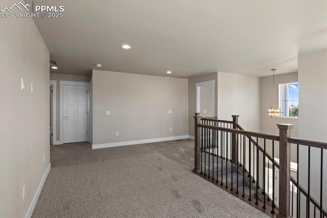 carpeted empty room featuring a chandelier