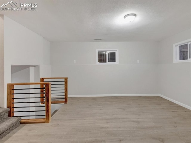 basement featuring a textured ceiling and light wood-type flooring