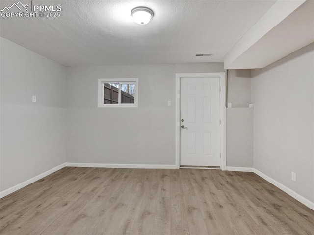 unfurnished room with a textured ceiling and light wood-type flooring