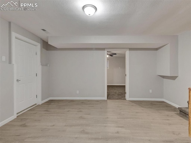 basement featuring a textured ceiling and light wood-type flooring