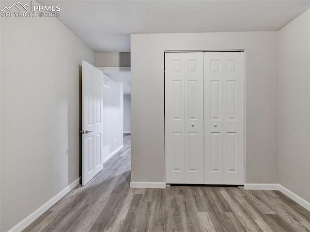 unfurnished bedroom with a closet and light wood-type flooring