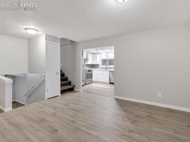 unfurnished living room with a textured ceiling and light wood-type flooring