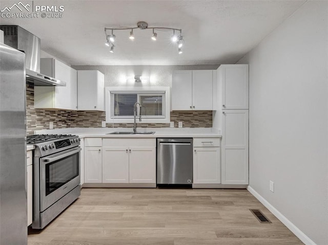 kitchen with white cabinetry, wall chimney exhaust hood, stainless steel appliances, and sink