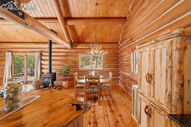 unfurnished dining area with beamed ceiling, log walls, light hardwood / wood-style flooring, and a wood stove