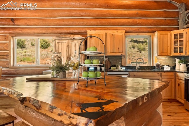 kitchen with dishwashing machine, sink, rustic walls, and light wood-type flooring