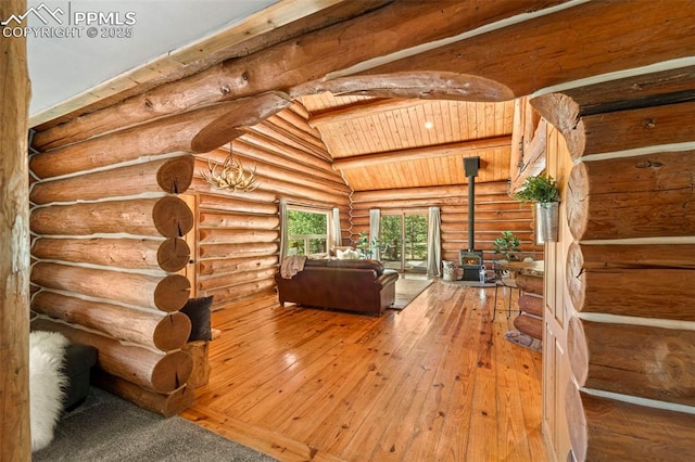 unfurnished living room featuring rustic walls, vaulted ceiling with beams, wood-type flooring, wooden ceiling, and a wood stove