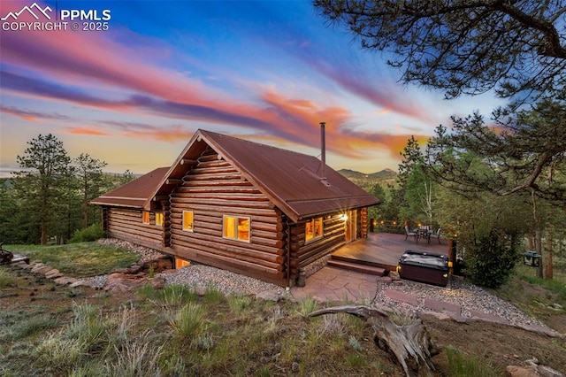 property exterior at dusk featuring a hot tub and a wooden deck