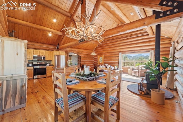 dining space with an inviting chandelier, high vaulted ceiling, light wood-type flooring, rustic walls, and beam ceiling