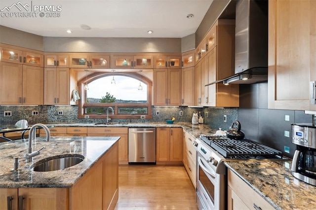 kitchen featuring wall chimney exhaust hood, appliances with stainless steel finishes, stone countertops, and sink