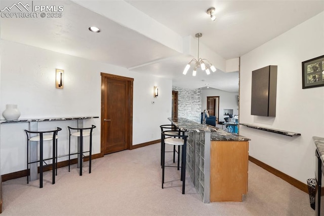 kitchen featuring vaulted ceiling, a breakfast bar, decorative light fixtures, dark stone countertops, and light carpet